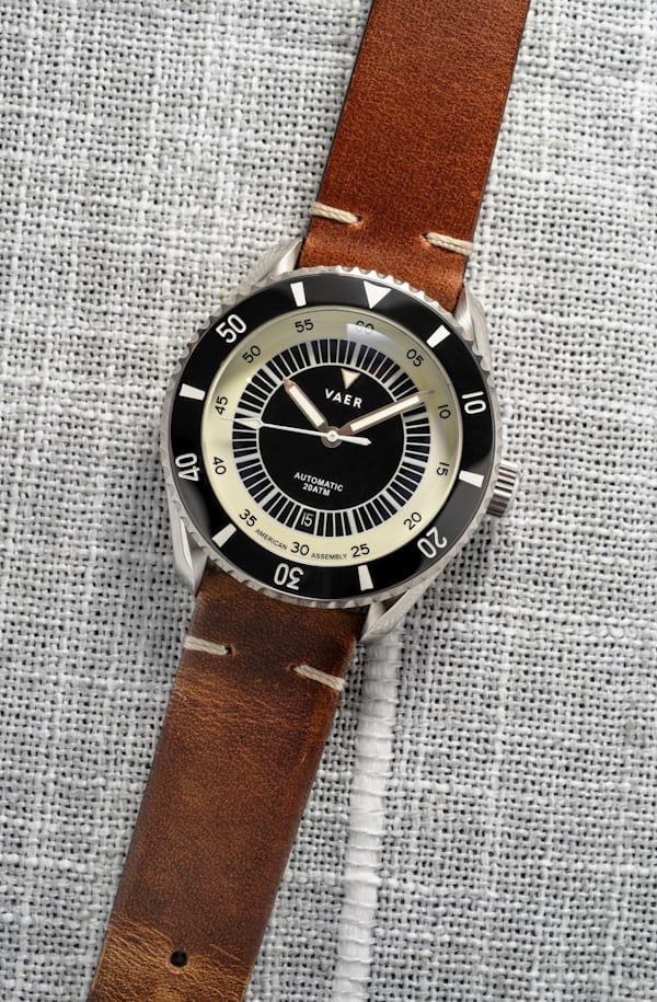 A black dial dive watch on a leather strap.