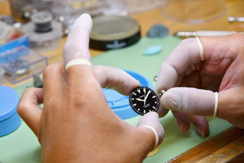 A watchmaker holds the dial of a watch. 
