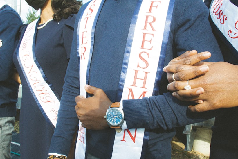 A person wearing a watch and a sash and a pair of hands in frame