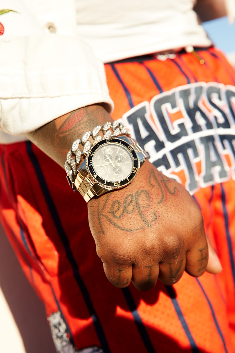 A person wearing a watch with a hand tattoo that says "keep it" 
