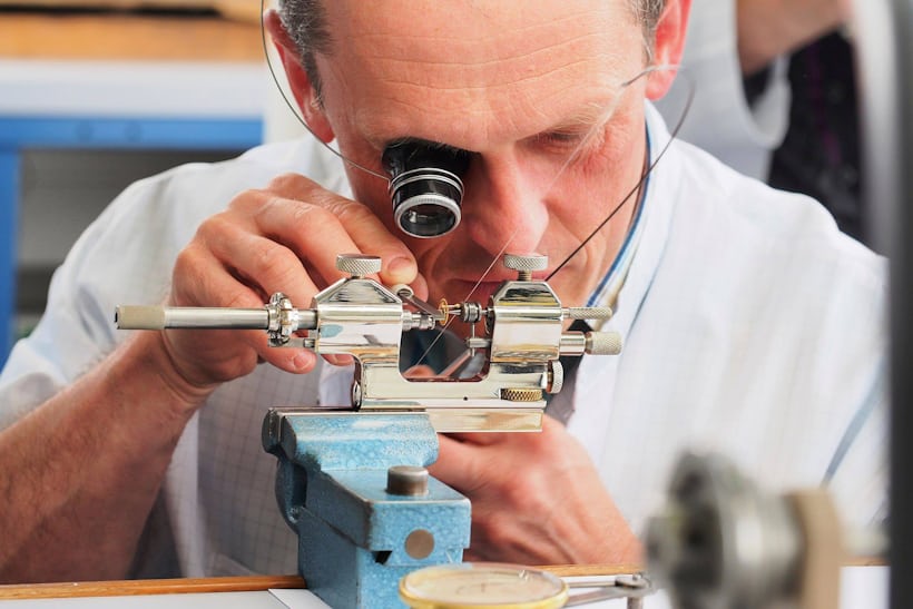 Watchmaker polishing a movement pivot by hand at Patek Philippe