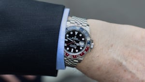 A man wearing a GMT-Master II on the wrist under a shirt and suit cuff.