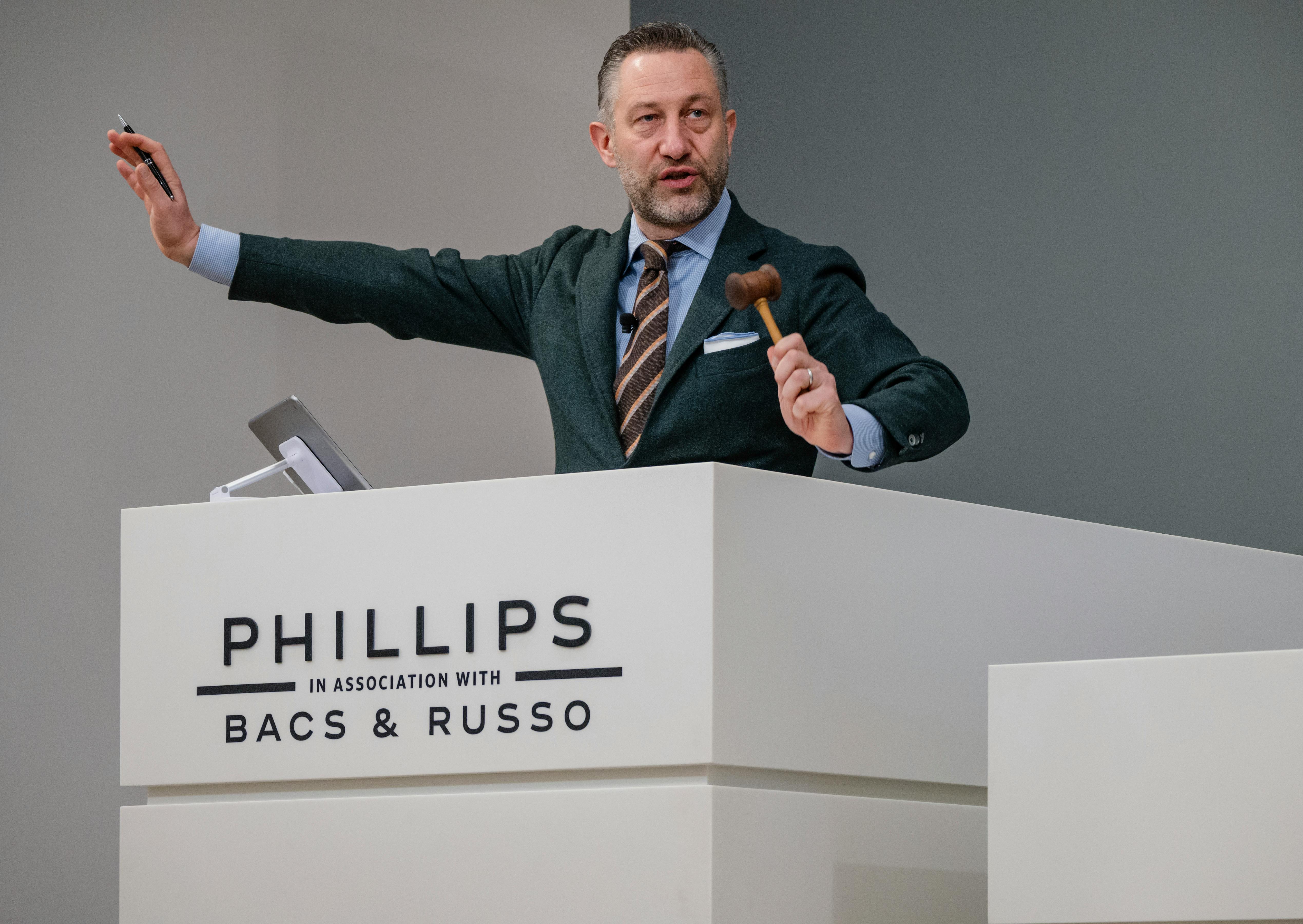 Aurel Bacs at the podium with gavel in the air. 