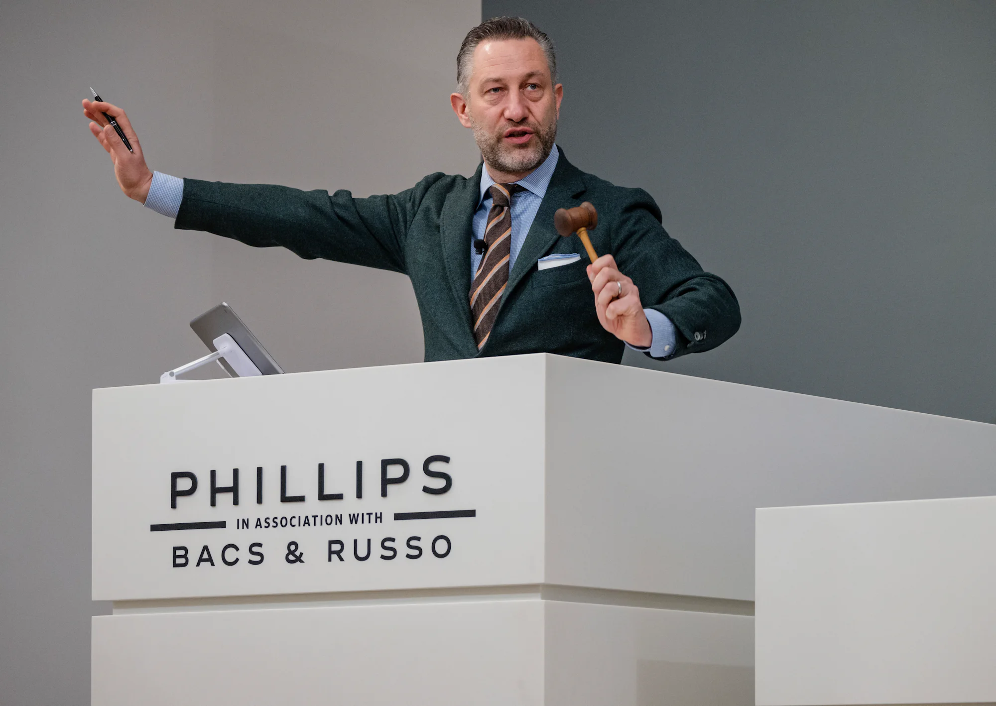 Aurel Bacs at the podium with gavel in the air.