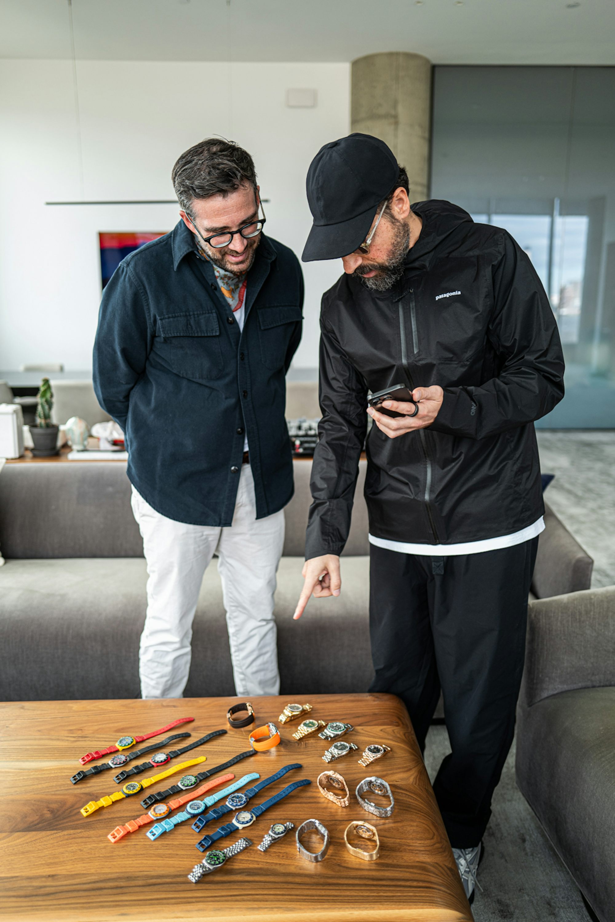 Ben and Ronnie look at Ronnie's watch collection laid out on a wooden coffee table