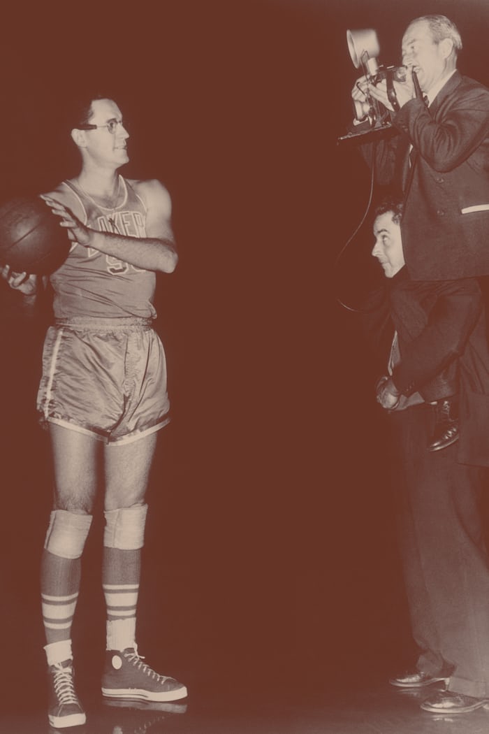 A man holding a basketball and another man taking his picture