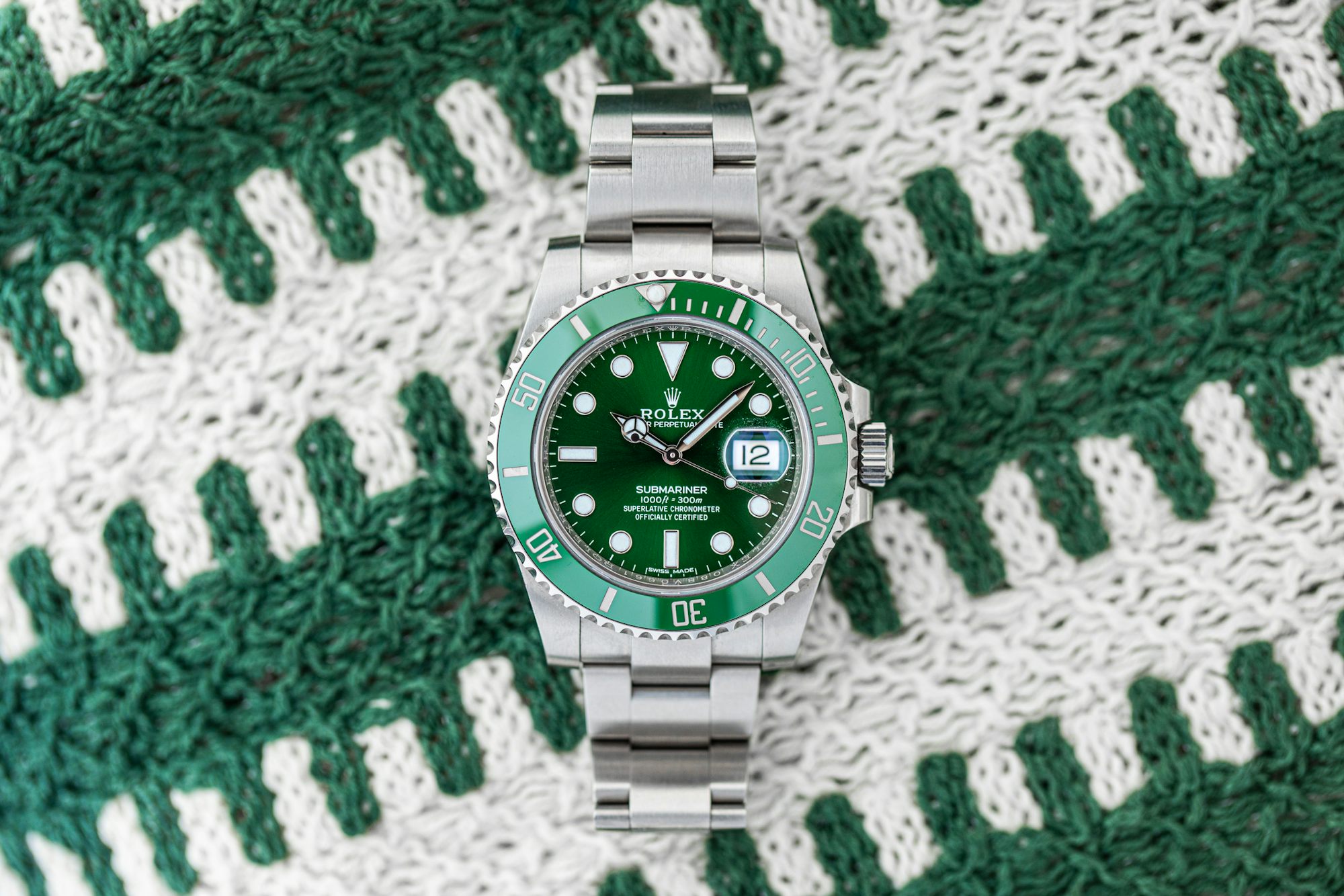 A green Rolex Submariner laid out on a knitted fabric