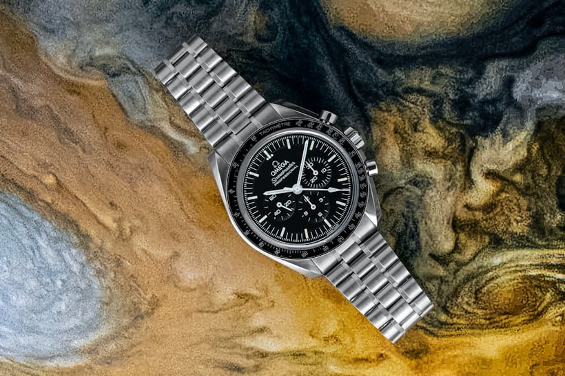 An Omega Speedmaster on bracelet laying down on colorful background.