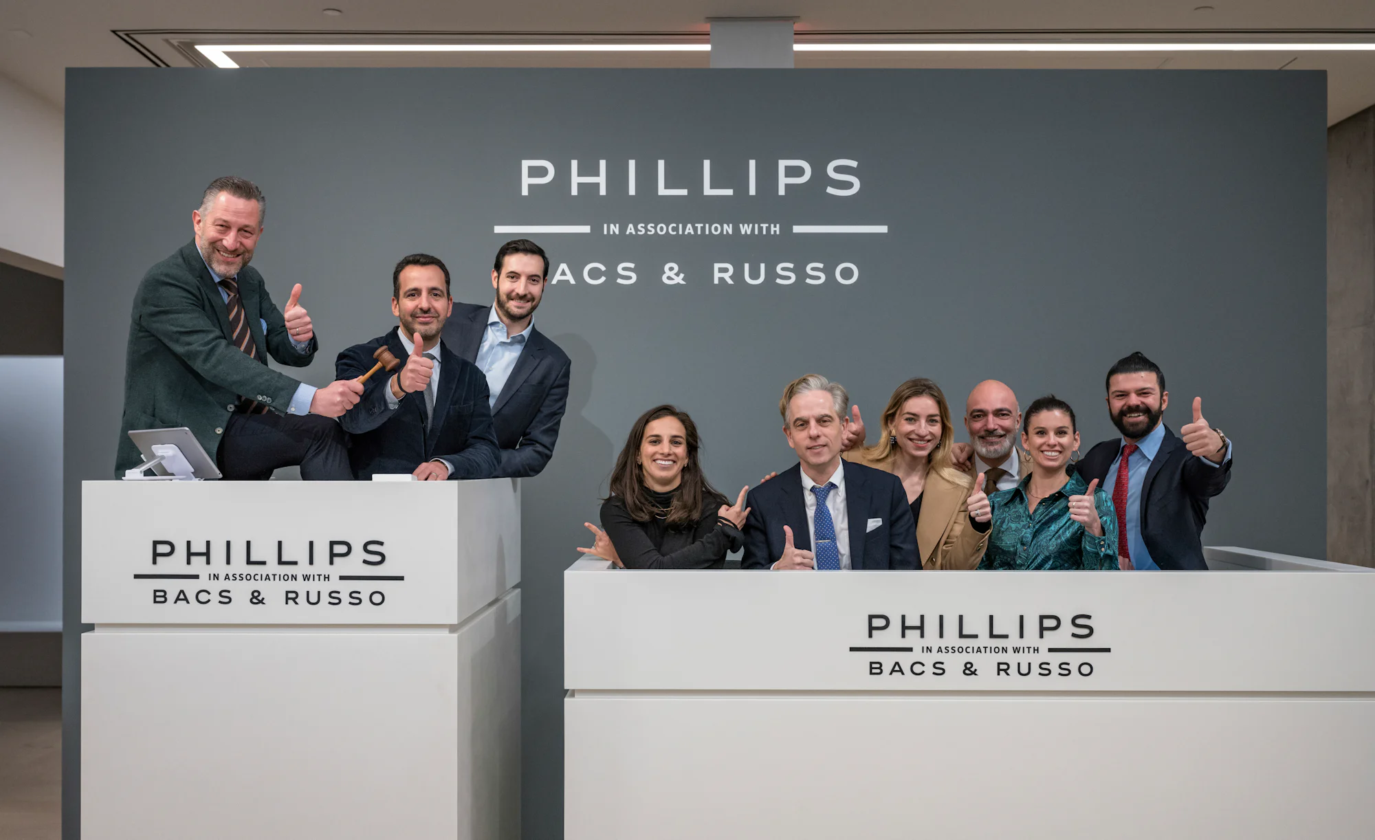 A group of nine people stand smiling at an auction podium.