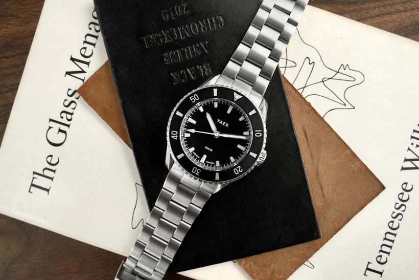 A black dial dive watch laying on top of a passport.