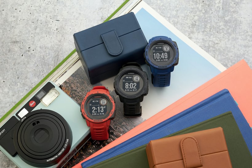 Three colorful variations of the Garmin Instinct Solar smartwatch are posed standing diagonally to each other. 