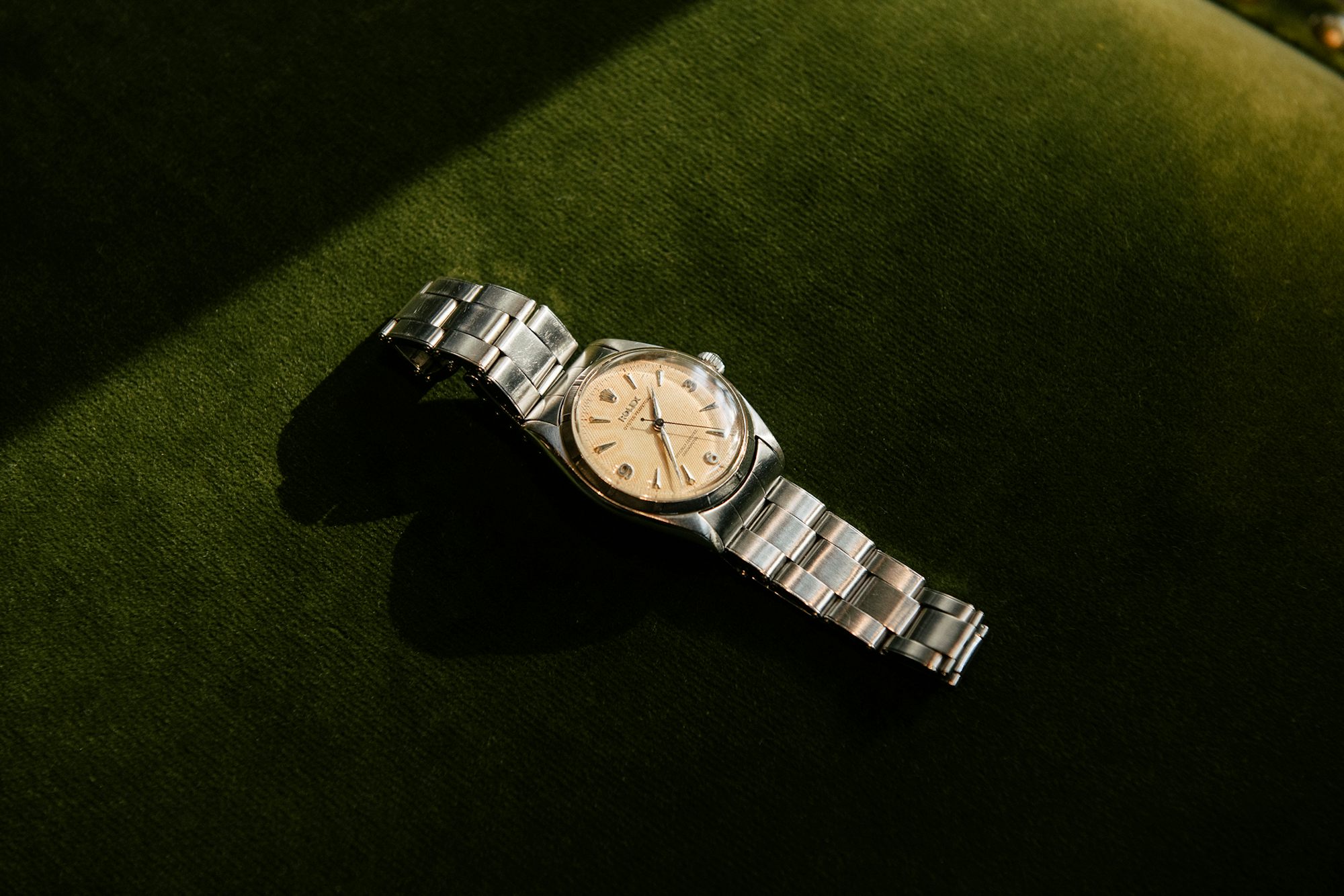 A Rolex watch on a green background