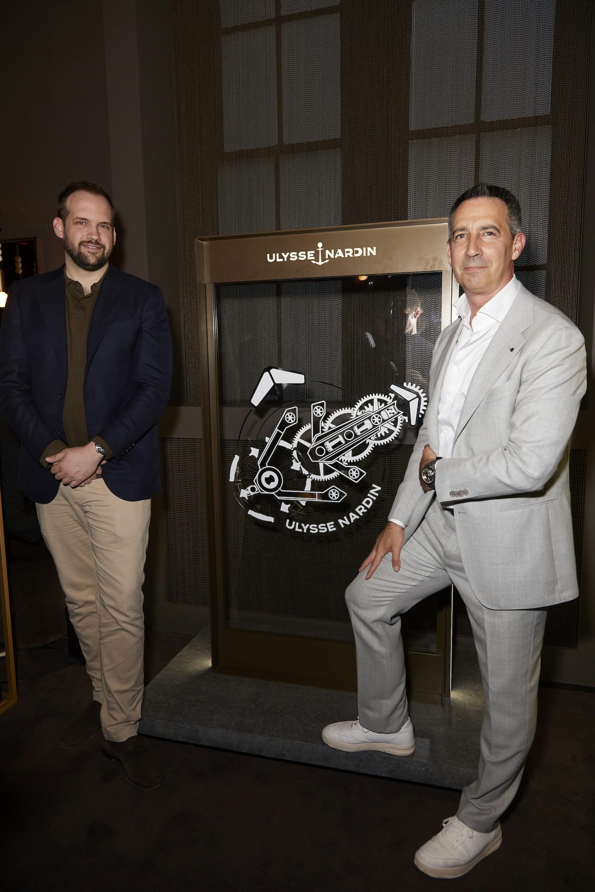 Mark Kauzlarich and FX standing in front of a Ulysse Nardin sign