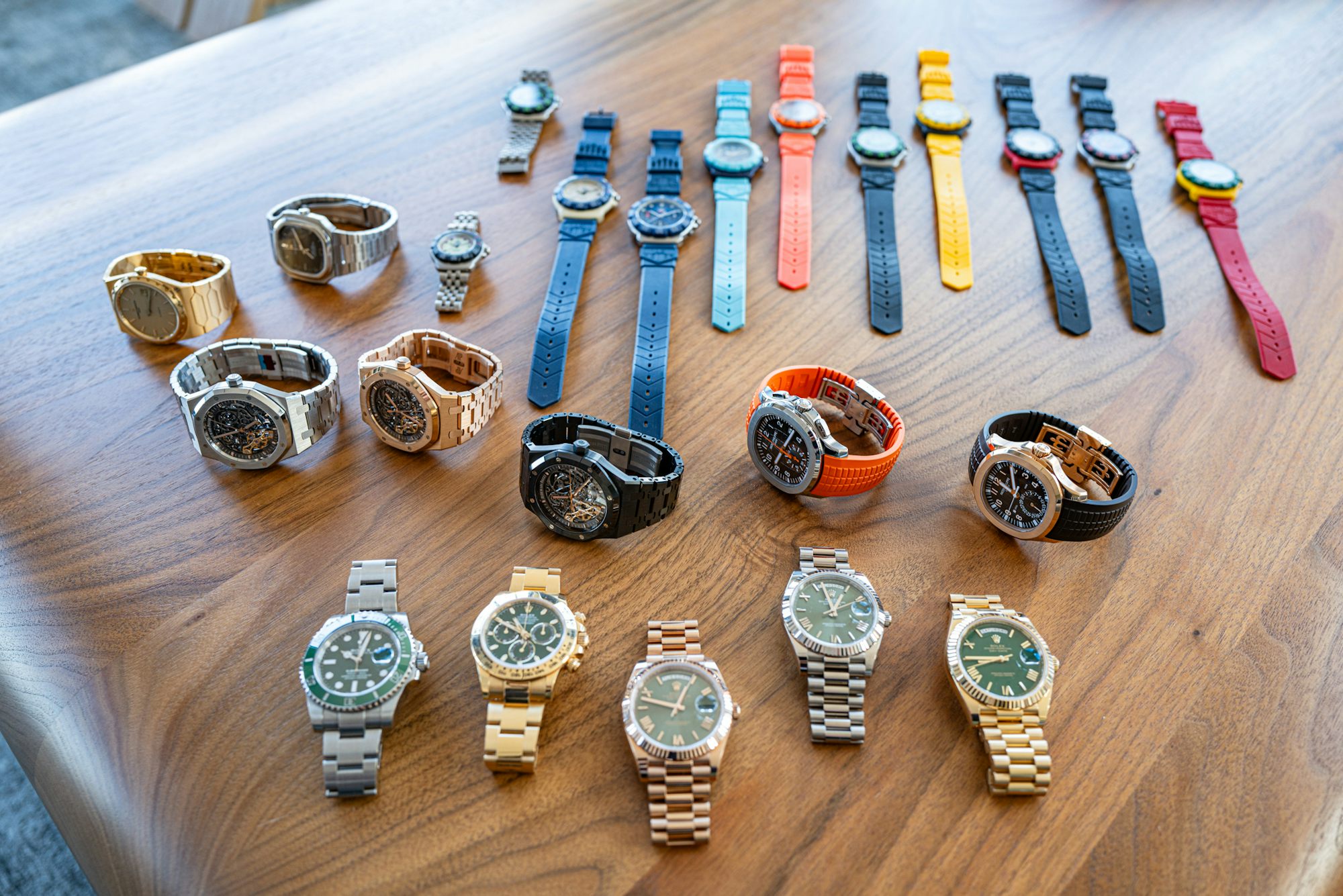A collection of watches in different metals, colors, and designs laid out on a wooden table