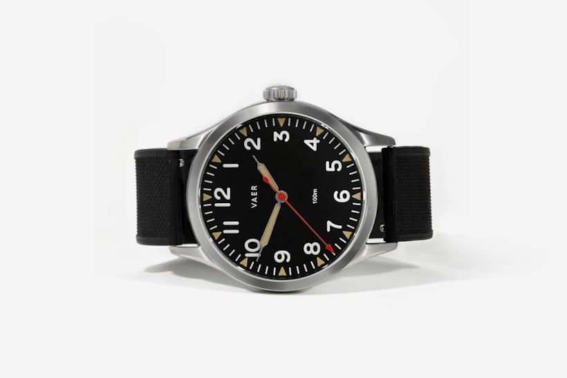A watch with a black dial laying on its side. 