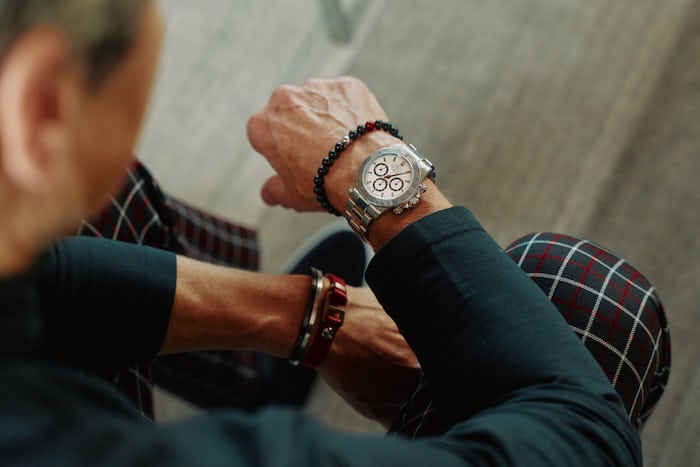 A person in plaid pants checks the Rolex on their wrist