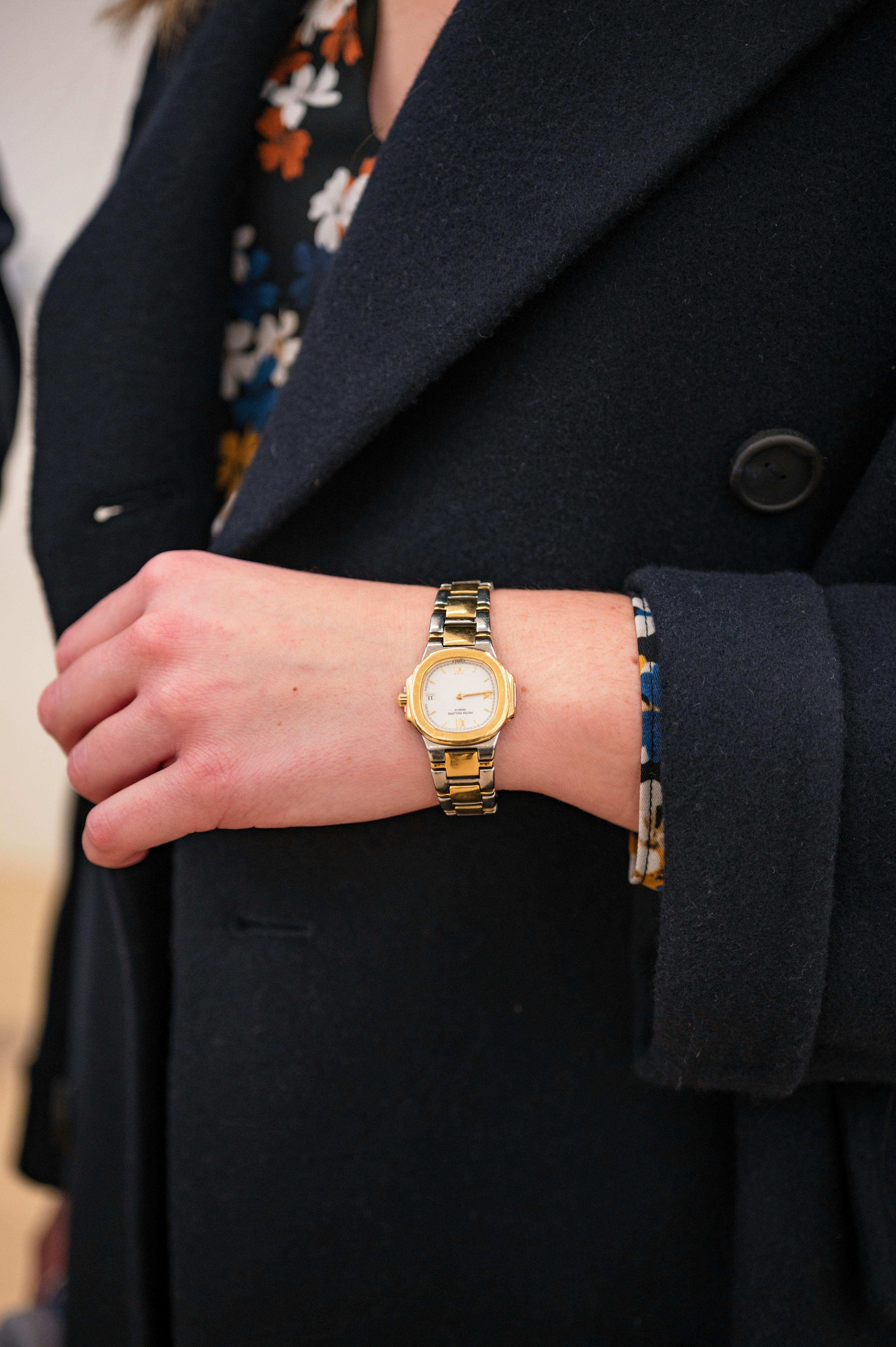 A woman in a black coat wears a Patek Philippe Nautilus 4700