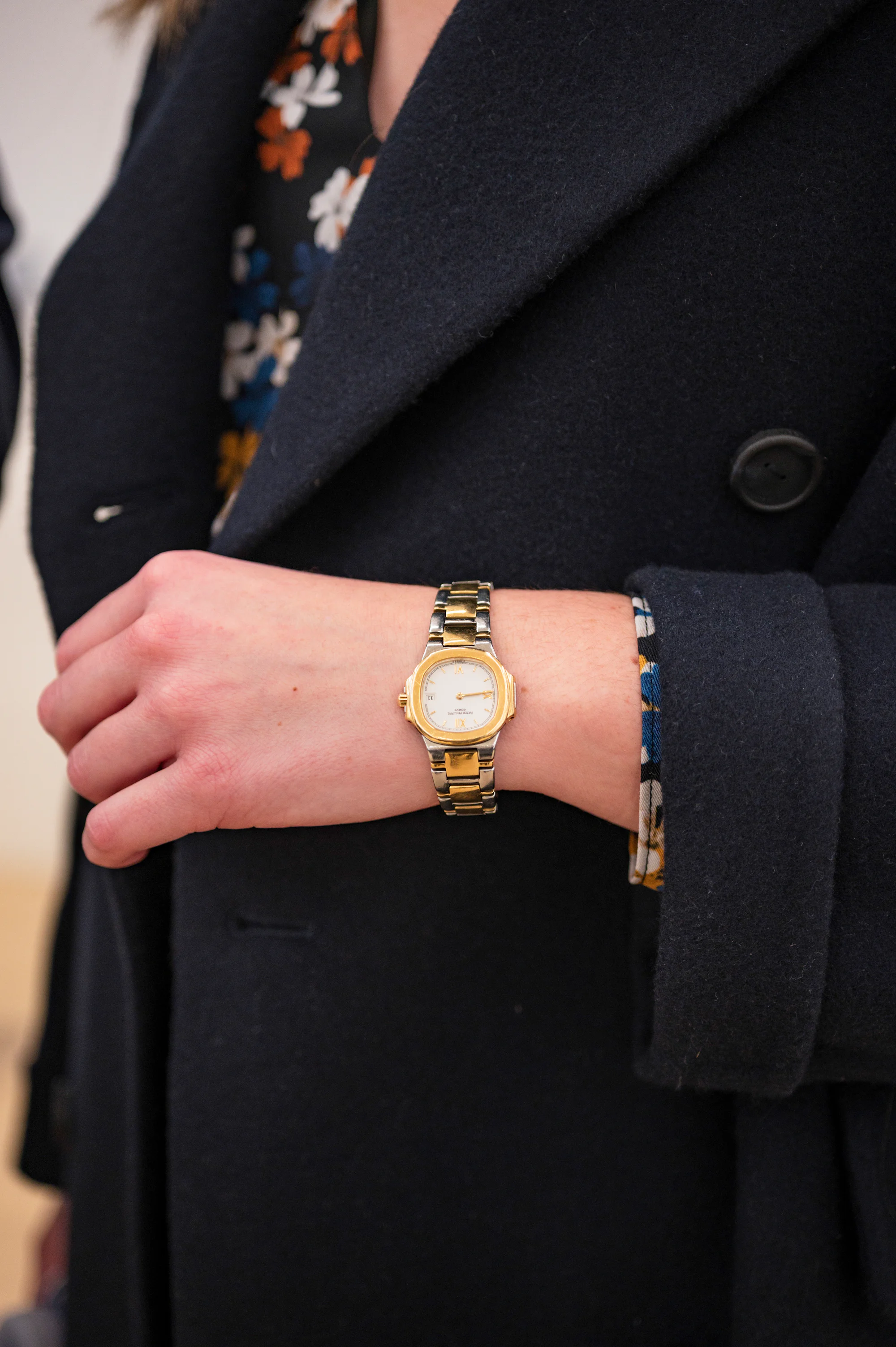 A woman in a black coat wears a Patek Philippe Nautilus 4700