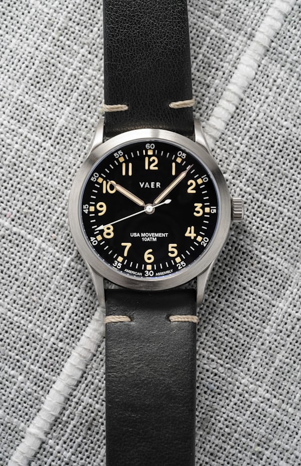 A black dial field watch on a leather strap.