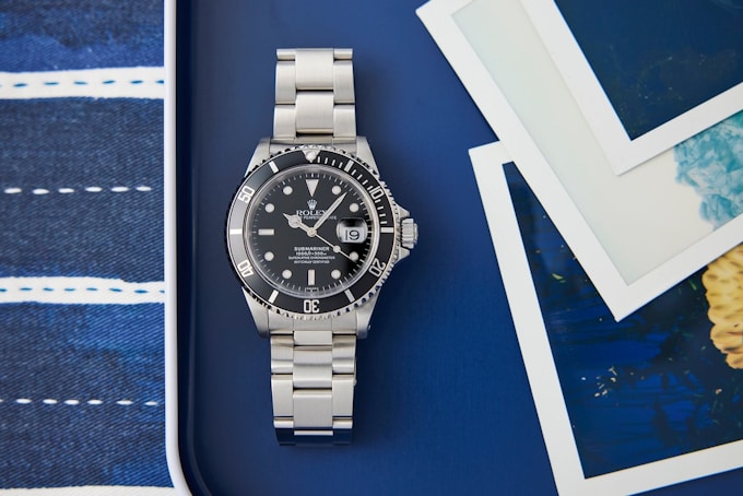 A Rolex Submariner sits on a blue background.